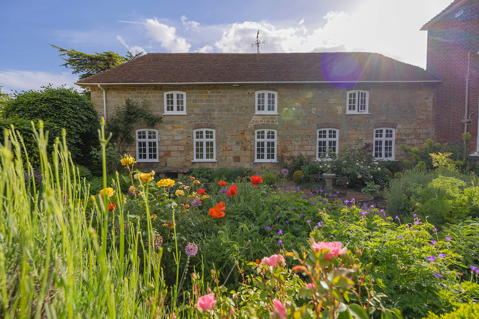 The side elevation of the manor house at Mountfield Winery with wild flowers and shrubbery in the foreground