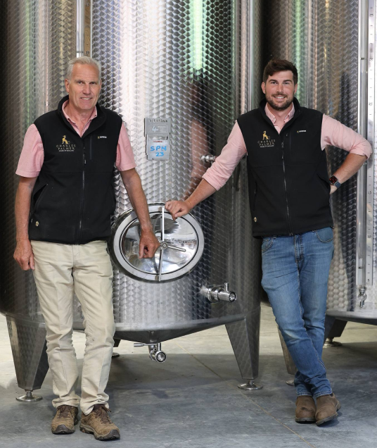 Charles Palmer Vineyards founder and son standing in front of a large fermentation tank