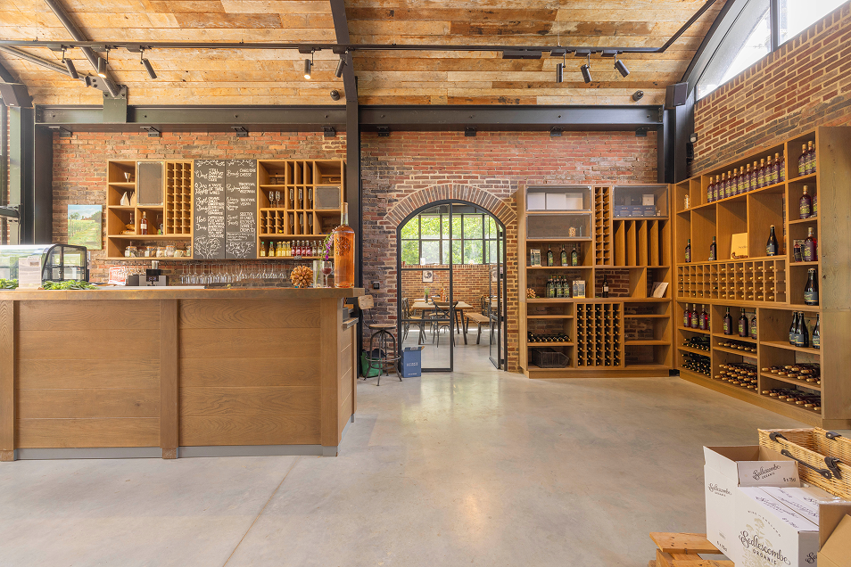 Inside Sedlescombe Organic Vineyard tasting room showing the wine on wood shelving and the bar area