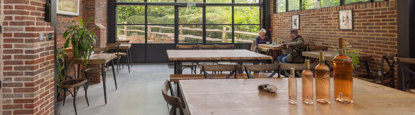 Inside Sedlescombe Organic Vineyard tasting room showing people sat down with bottles of wine in the foreground